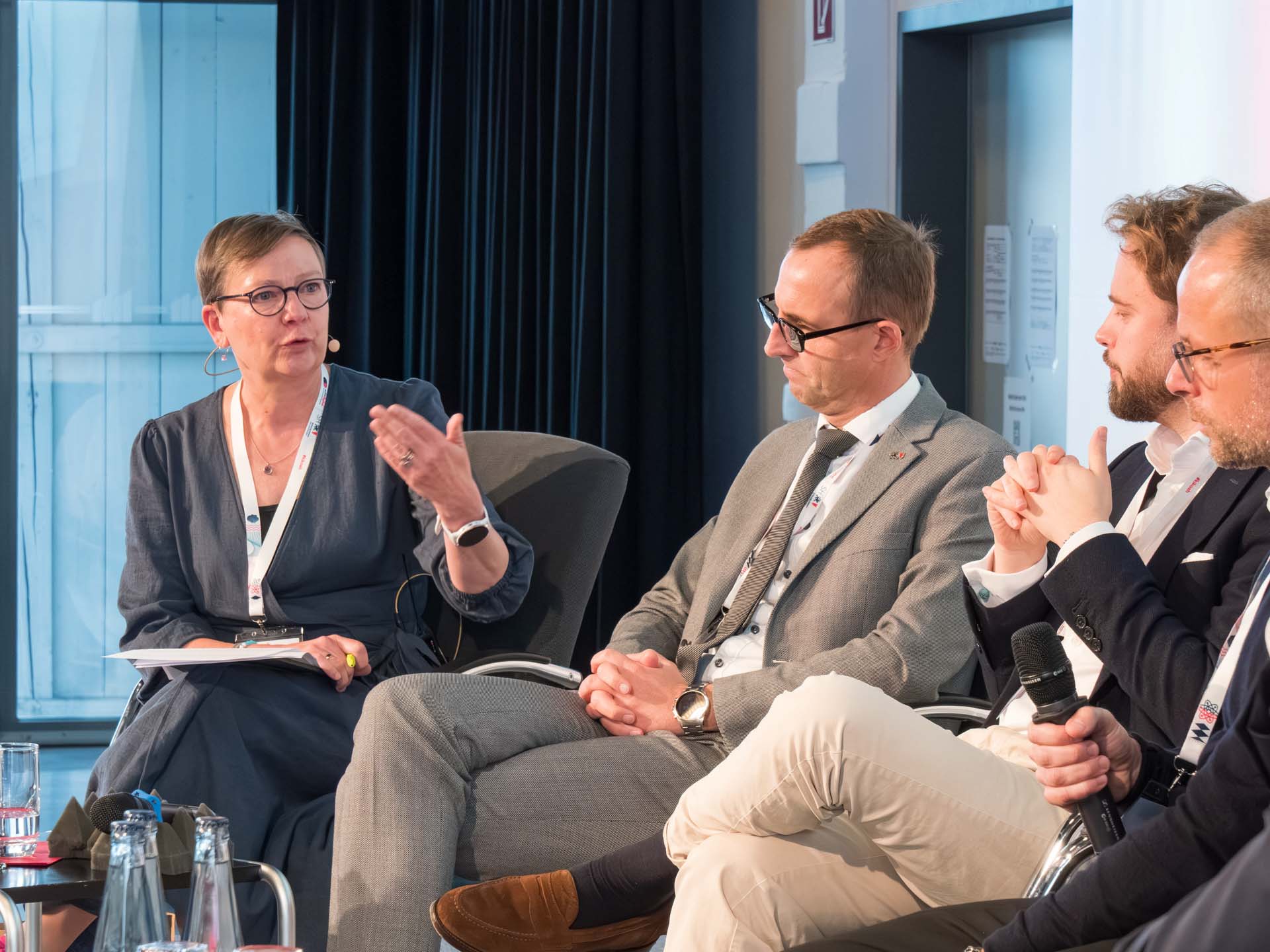 Eine Frau und drei Männer sitzen auf einem Diskussions-Panel